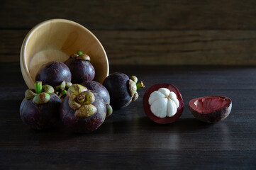Fresh mangosteen Thai fruits in wooden bowl put on wooden table and old wooden wall