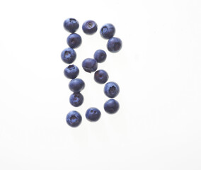 The letter B spelt out in blueberries against a white background