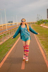 mujer joven hermosa con ante ojos patinando al aire libre con sus patines , usa unas medias altas de colores 
