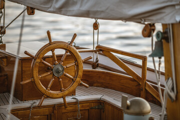 A close-up of instruments and wooden wheel of nautical vessel. Sailboat at sea background