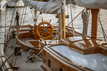 A close-up of instruments and wooden wheel of nautical vessel. Sailboat at sea background