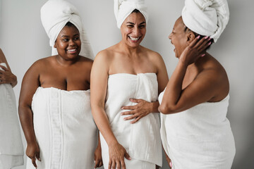 Multigenerational women laughing together while wearing body towels - Main focus on center female face