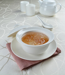 luxury chilled sweet fresh bird nest soup with almond paste and peach resin in bowl and pink table cloth halal healthy dessert menu