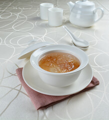 luxury chilled sweet fresh bird nest soup with almond paste and peach resin in bowl and pink table cloth halal healthy dessert menu