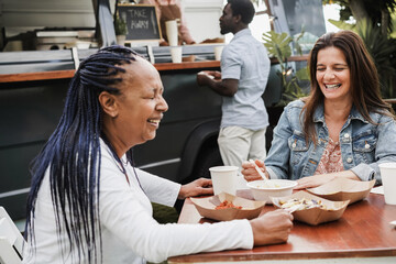 Multiracial people eating at food truck restaurant outdoor - Focus on caucasian woman face