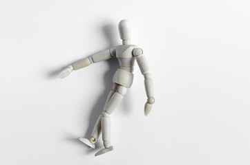 Abstract figure of a wooden man lying on a light background. The figure of a wooden man on a light background close-up
