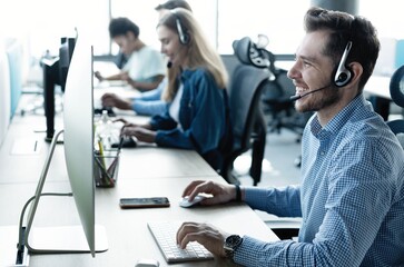 Young handsome male customer support phone operator with headset working in call center