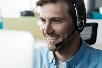 Young handsome male customer support phone operator with headset working in call center