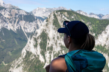 A woman with a hiking backpack admiring the view on the Alpine mountain chains in Austria, Hochschwab region. The slopes are partially overgrown with small bushes, higher parts baren. Happiness