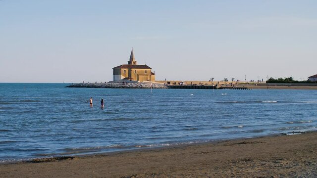 A small church on the beach in the Italian town Caorle in Veneto, Italy. The coastal Catholic chapel during sunset is a famous landmark and tourist attraction during the summer holidays. 4K.