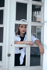 a woman in a dress and a white shirt, with a white hoop on the stairs with white doors. Frenchwoman, lady,
