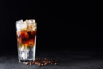 Cold drink with espresso and tonic in glass on black background