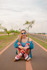 Fototapeta premium mujer joven hermosa con ante ojos sentada al aire libre con sus patines , usa unas medias altas de colores 