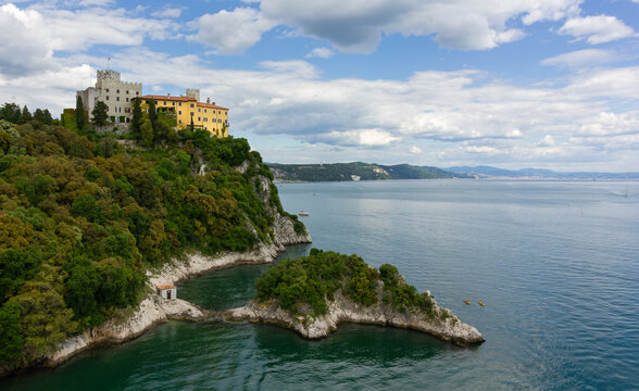 Castle of Duino on the rocky promontory on the Adriatic coast near Trieste, Italy, with the city skyline far in the background