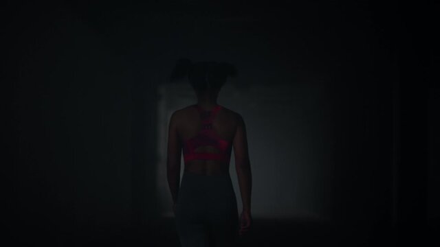 Girl walking in dark corridor. Athlete taking break after cardio workout