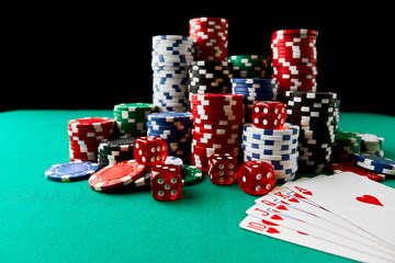 Casino chips, playing cards and dices on green fabric table