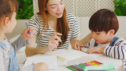 Asian boy and girl sit at desk study online on laptop, smart little kids handwrite in notebook learning using internet lessons on quarantine, homeschooling concept.
