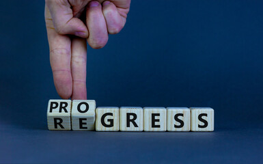 Regress or progress symbol. Businessman turns wooden cubes and changes the word 'regress' to 'progress'. Beautiful grey table, grey background, copy space. Business, regress or progress concept.