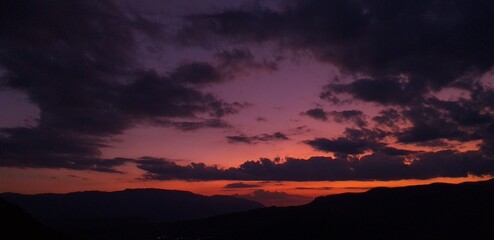 beautiful view of sunset in orange, purble and blue colours showing also mountains and clouds
