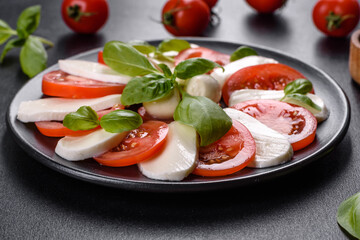 Italian caprese salad with sliced tomatoes, mozzarella cheese, basil, olive oil