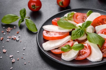 Fototapeta na wymiar Italian caprese salad with sliced tomatoes, mozzarella cheese, basil, olive oil