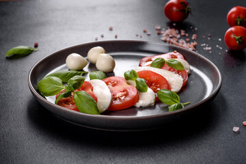 Italian caprese salad with sliced tomatoes, mozzarella cheese, basil, olive oil