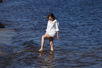 Pretty woman in white shirt playing with water in the sea