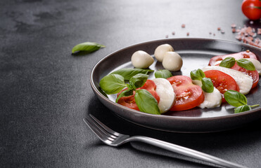 Italian caprese salad with sliced tomatoes, mozzarella cheese, basil, olive oil