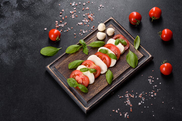 Italian caprese salad with sliced tomatoes, mozzarella cheese, basil, olive oil