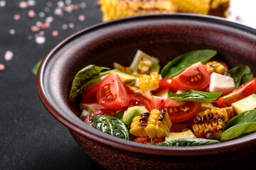Delicious fresh salad with tomatoes, avocado, cheese and grilled corn with olive oil