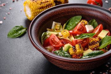 Delicious fresh salad with tomatoes, avocado, cheese and grilled corn with olive oil