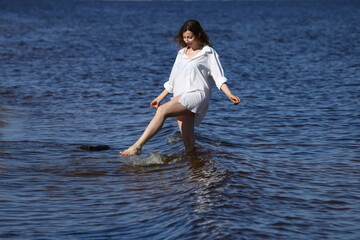 Pretty woman in white shirt playing with water in the sea
