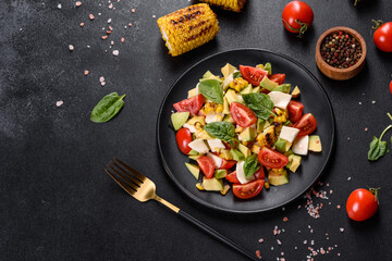 Delicious fresh salad with tomatoes, avocado, cheese and grilled corn with olive oil