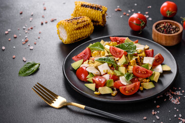 Delicious fresh salad with tomatoes, avocado, cheese and grilled corn with olive oil