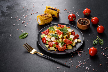 Delicious fresh salad with tomatoes, avocado, cheese and grilled corn with olive oil