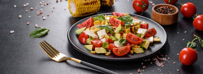 Delicious fresh salad with tomatoes, avocado, cheese and grilled corn with olive oil