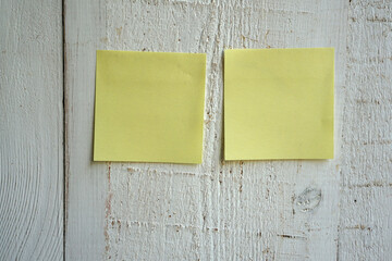 Blank sticky note pasted on a white wooden wall, can be used for various kinds of notes or reminders             