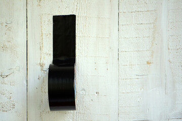 Black duct tape stuck to the wooden wall          
