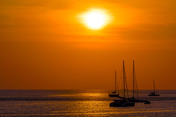 Silhouette of boat on sea beach with sunset background in Phuket Island, Thailand