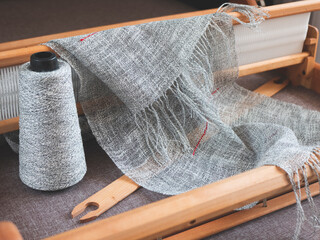 Wooden handloom, reed, shuttle, bobbin with linen yarn and piece of woven cloth. Handwoven fabric...