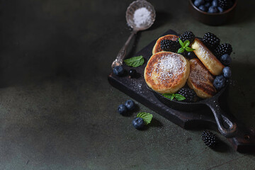 Obraz premium Curd pancakes or syrniki with fresh berries on a concrete background. Ukrainian, Russian cuisine sweet food. Delicious healthy breakfast.