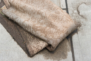 old, soggy decomposing carpet left at the curb side for garbage collection