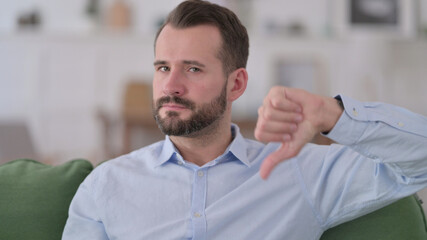 Young Man with Thumbs Down at Home 