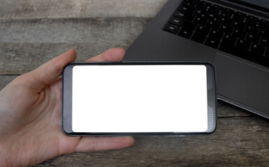 Mockup image of hand holding horizontal mobile phone on workplace desk. Phone Blank Screen On Wood Table, Mockup Phone.