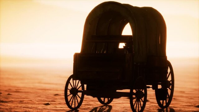 canvas covered retro wagon in desert at sunset