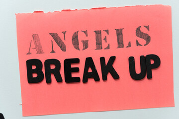 message with the words angels (in stencil) and break up in all caps, black chalk letters on deep coral pink and gray paper background