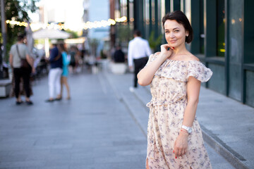 an adult contented woman in a dress stands in the middle of an urban street against the backdrop of lanterns. place for your design