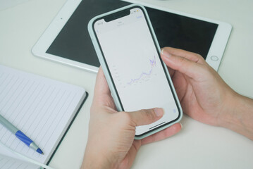 phone in hand with a graphic, a tablet and a notebook 