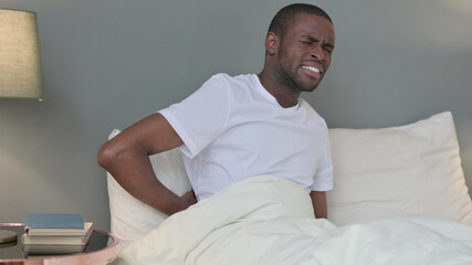 Exhausted Young African Man having Back Pain in Bed 