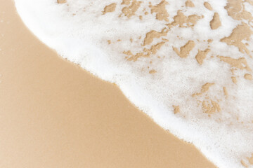 White foam wave on beach top view, beautiful natural scene of tropical summer background for relaxing vacation, ocean waves crashing on sand beach island with copy space.
